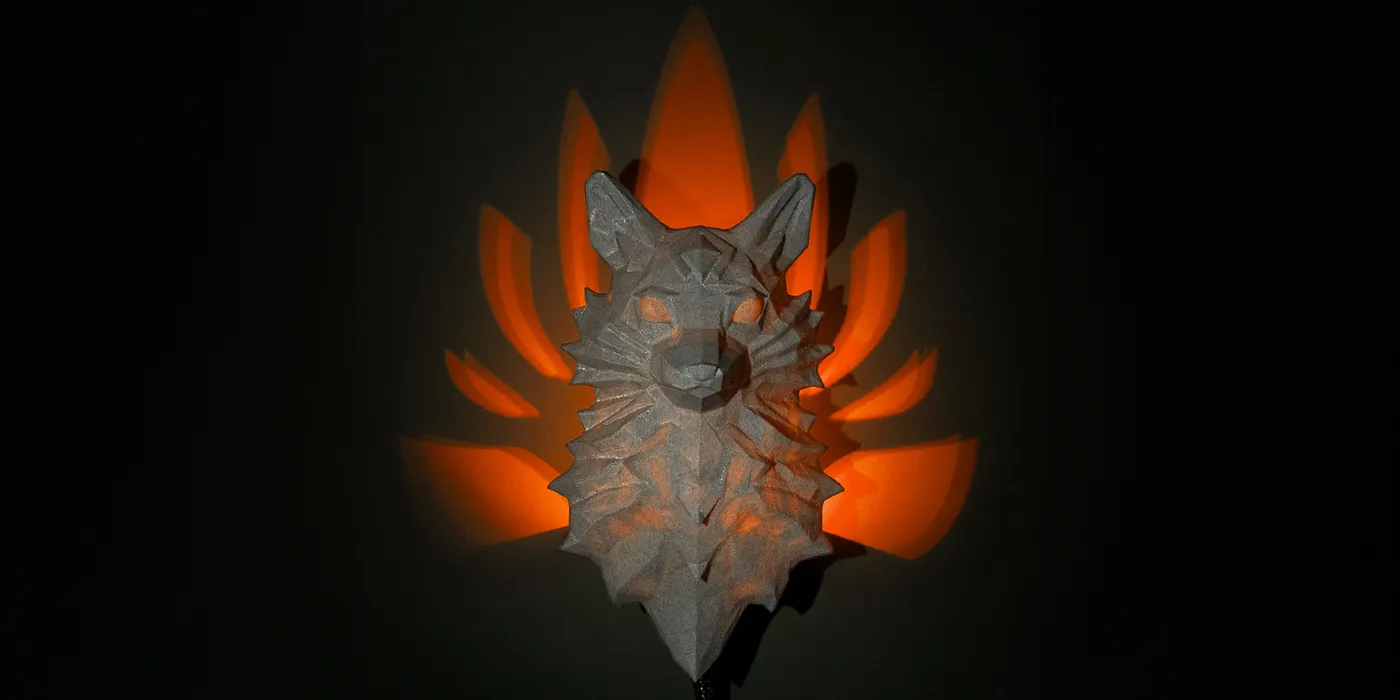 3D printed nine-tailed fox wall light casting orange tail shadows on a dark wall