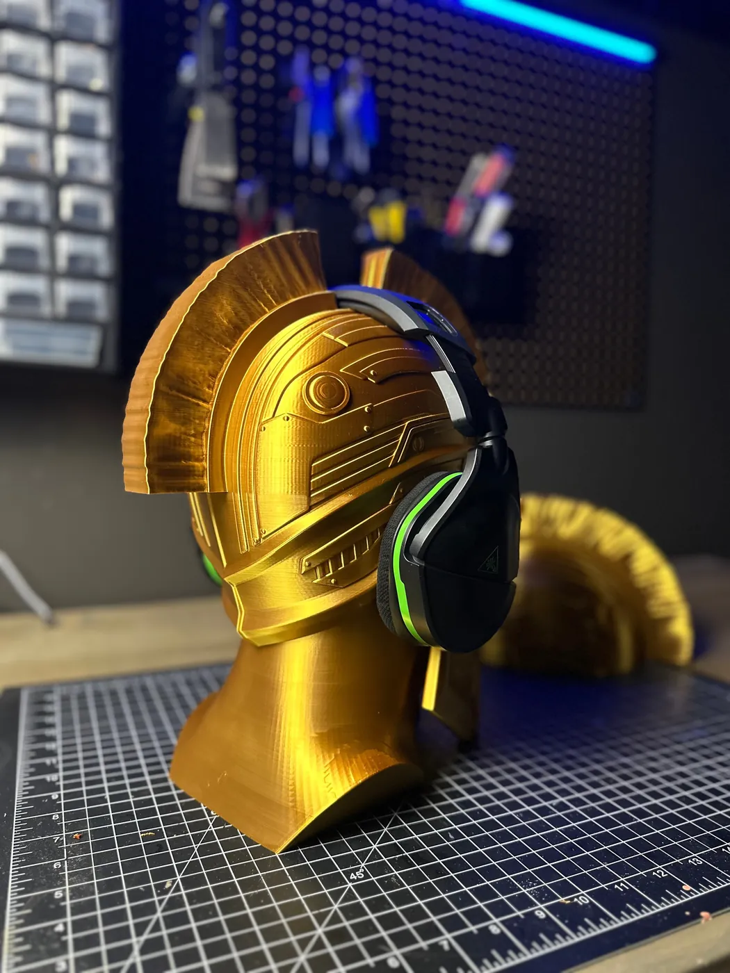 Gold 3D printed Spartan bust holding a pair of gaming headphones