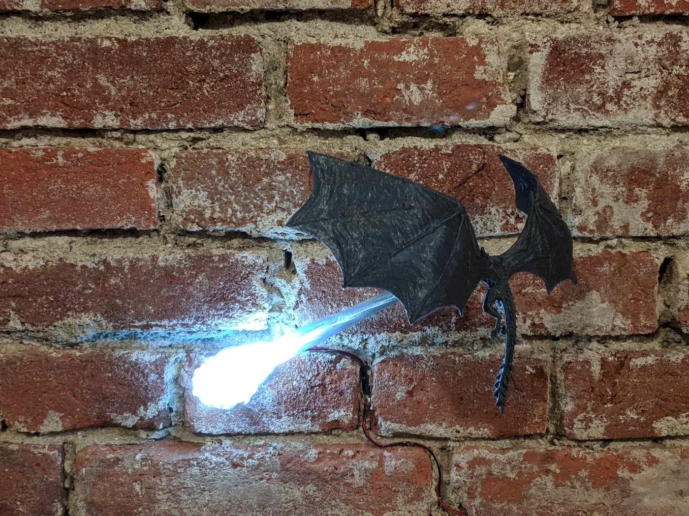 3D printed dragon wall lamp breathing white light on a brick wall