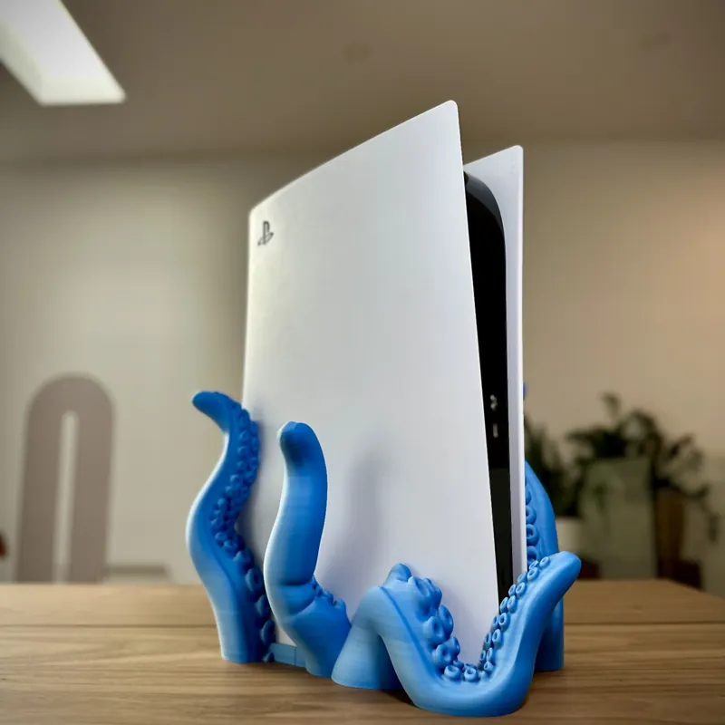 Blue 3D printed octopus tentacle stand holding a game console