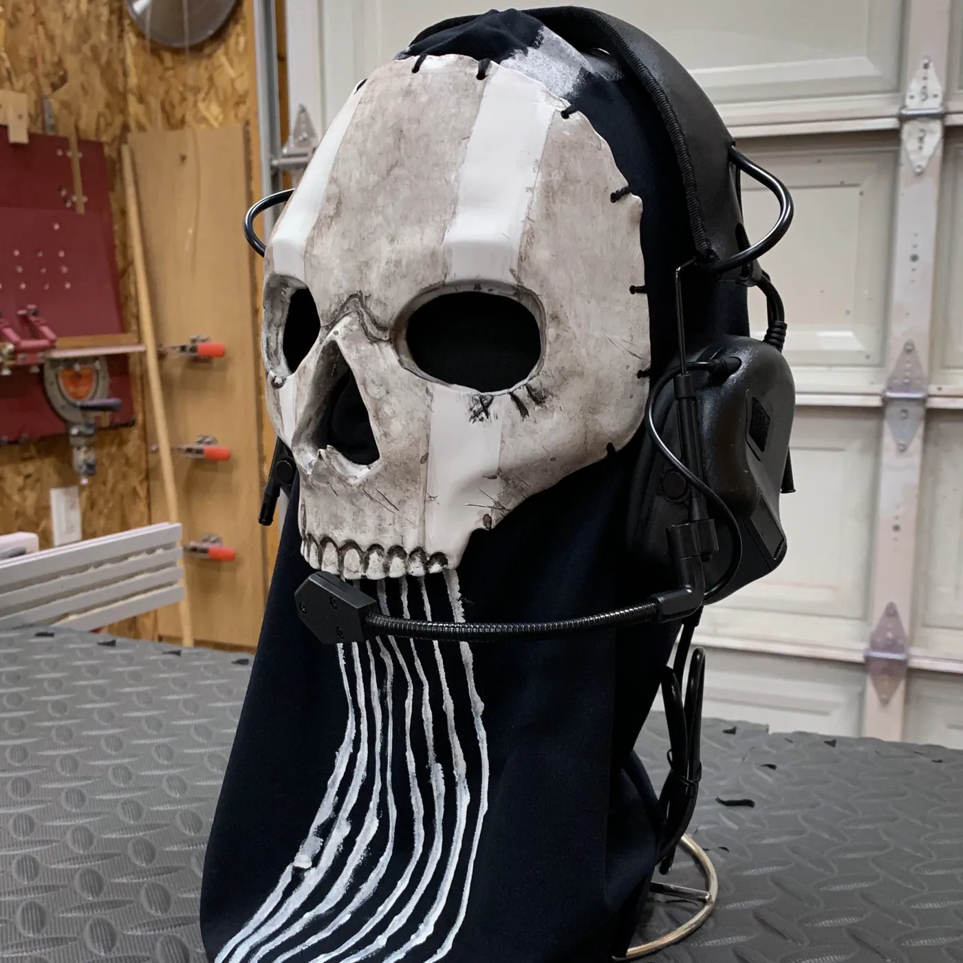 Painted 3D printed skull cosplay mask with tactical headset on a stand