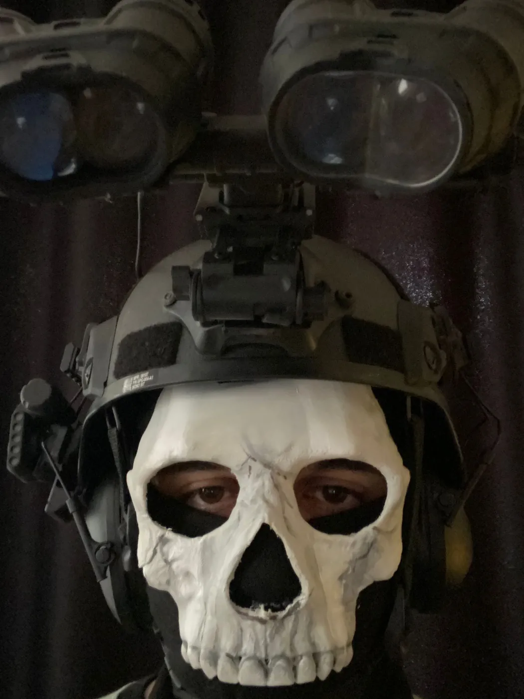 Person wearing a 3D printed skull mask with tactical helmet and night-vision goggles
