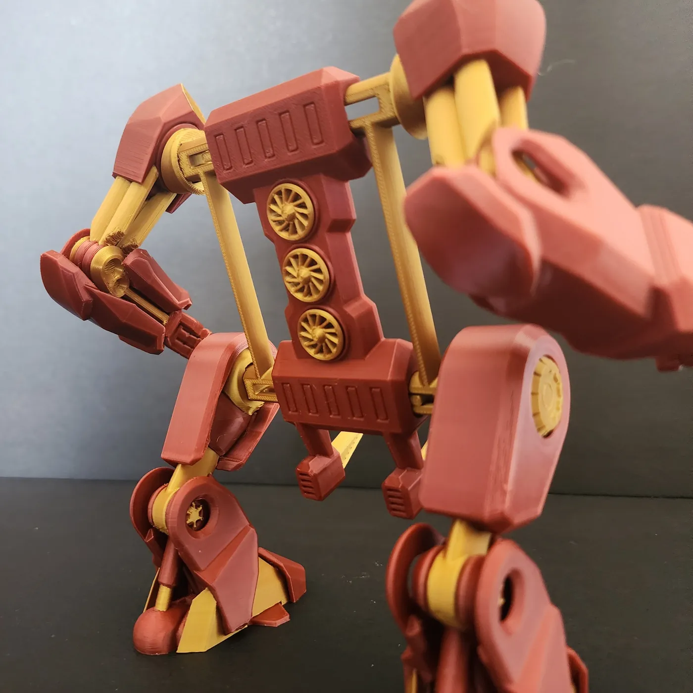 Red and gold 3D printed robot exo-suit phone stand, close-up of the frame