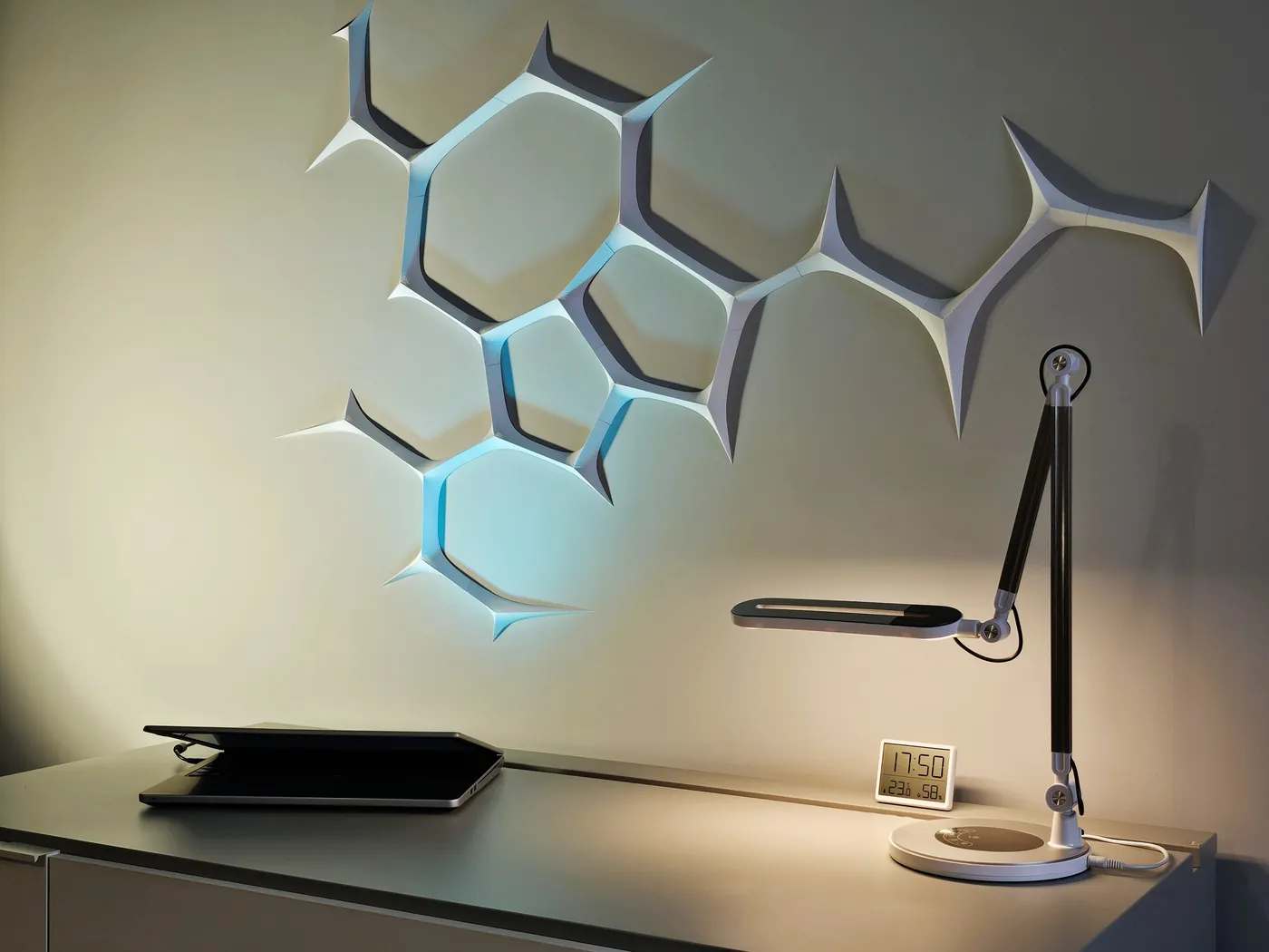 Backlit 3D printed neural network wall art above a desk with a lamp