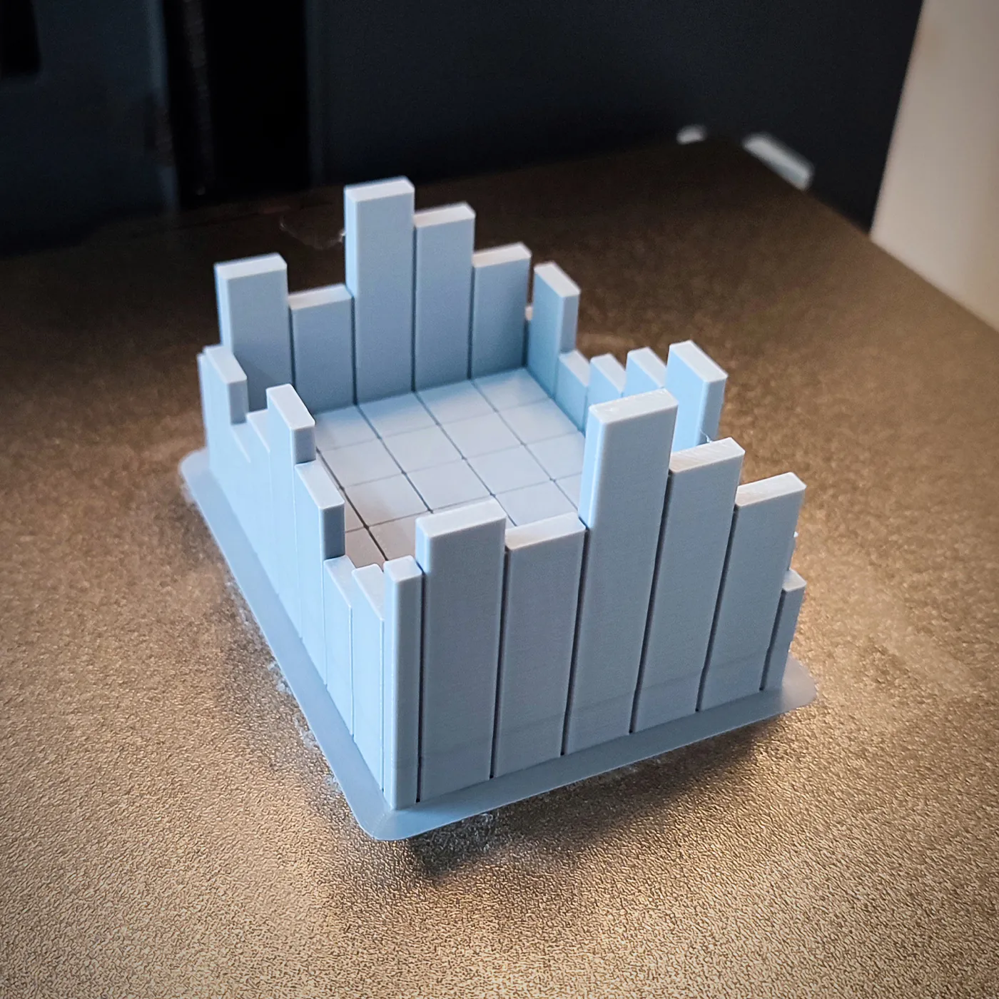 Blue 3D printed stepped pixel-block part on a print bed